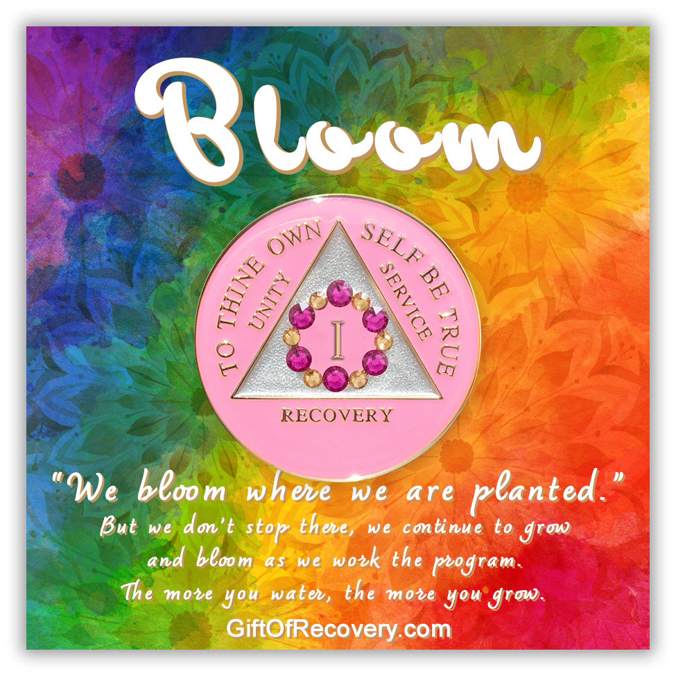 1 year AA medallion princess pink with 6 fuchsia pink genuine crystals and 6 gold to form a circle around the roman numeral to represent bloom, we grow and blossom when we work the program, triangle is pearl white with the AA slogan and three legacies embossed in 14k gold-plated brass, sealed with resin for a glossy finish, featured on a tie-dye 3x3 card with silhouettes of flowers and a description paragraph.