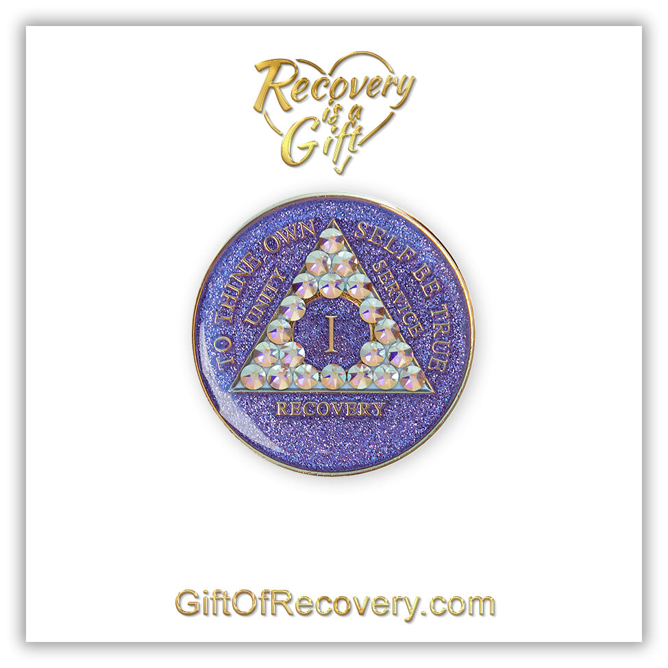 1 year AA medallion Purple glitter with 21 Aurora Borealis genuine crystals in the shape of the triangle, to thine own self be true, unity, service, recovery, the outer rim, and the roman numeral are embossed with 14k gold-plated brass, the recovery medallion is sealed in resin for a shiny finish that lasts, the medallion is featured on a white 3x3 card with recovery is a gift going through a heart at the top center, and giftofrecovery.com on the bottom, both are in the color gold.