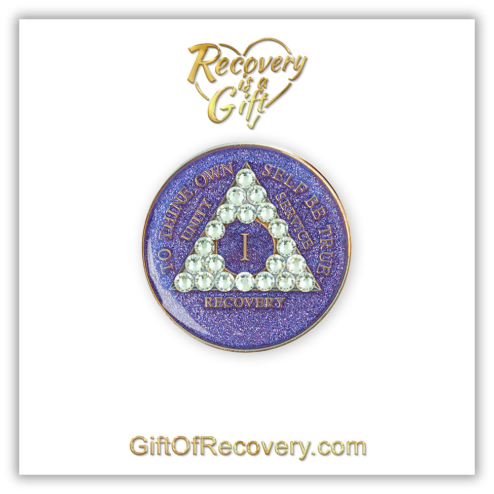 1 year AA medallion purple glitter with 21 genuine diamond CZ crystals in the shape of the triangle, with to thine own self be true, unity, service, recovery, and the roman numeral embossed with 14k gold-plated brass, the recovery medallion is sealed with resin for a shiny finish that will last and is scratch proof, the medallion is featured on a white 3x3 card with Recovery is a Gift going through a heart at the top and GiftOfRecovery.com at the bottom, both writings are in the color gold.