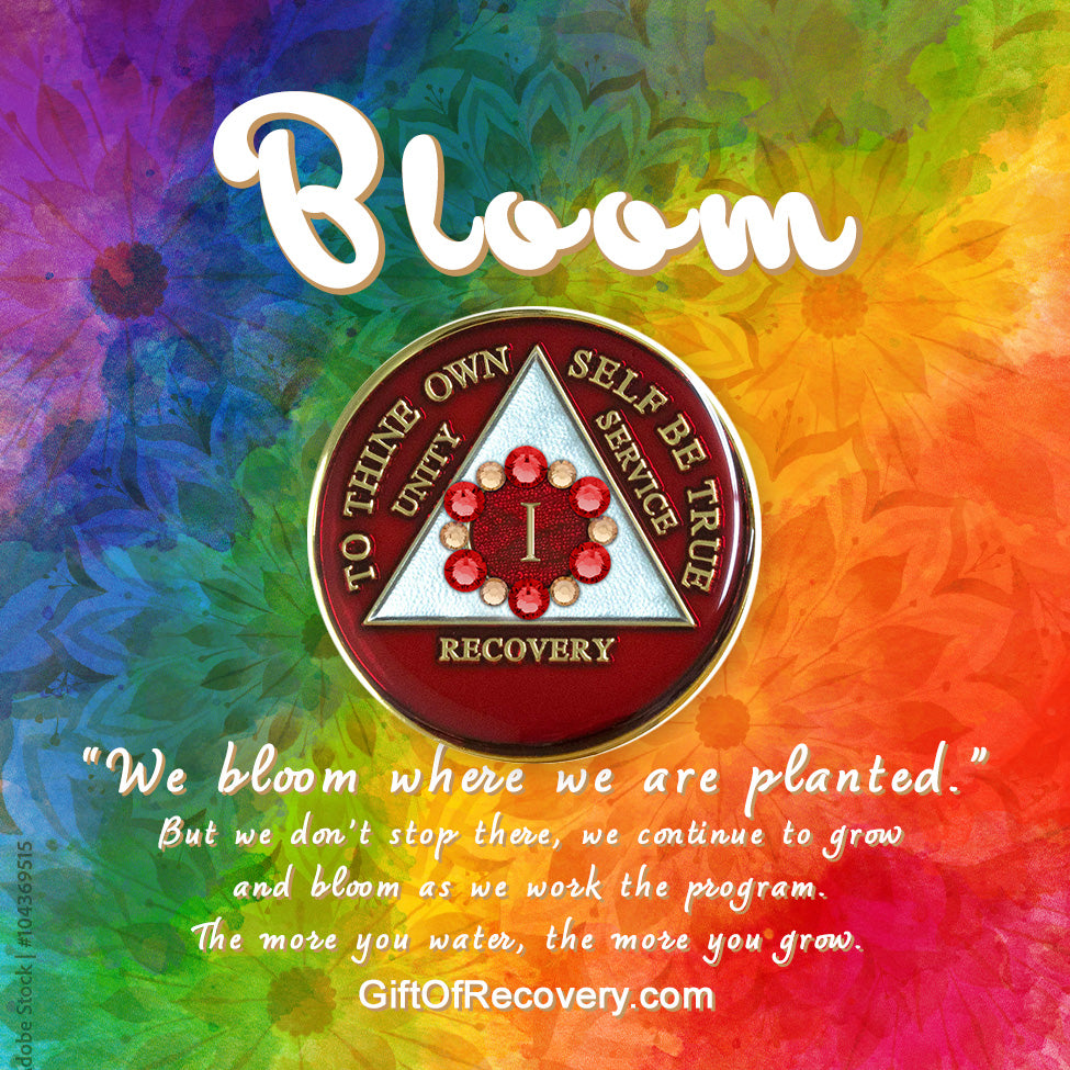 1 Year AA medallion ruby red with 6 ruby red genuine crystals and 6 gold in a circle around the roman numeral symbolizing we bloom where we are planted, the triangle is pearl white with to thine own self be true, unity, service, recovery embossed with 14k gold-plated brass, featured on a bold tie-dye 3x3 card with silhouettes of flowers and Bloom in white with a paragraph outlining growing in recovery.