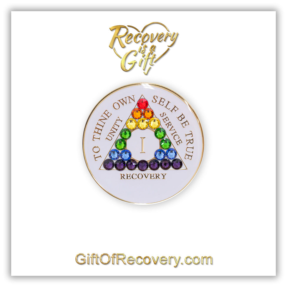 1 year AA medallion pearl white with 21 genuine crystals in the colors of the rainbow, symbolizing renewal and self-discovery, to thine own self be true, unity, service, recovery and roman numeral are embossed with 14k gold-plated brass, sealed in a high-quality, chip and scratch-resistant resin dome giving it a beautiful glossy look that will last, recovery medallion featured on a white 3x3 card with recovery is a gift going through a heart at the top and giftofrecovery.com at the bottom.