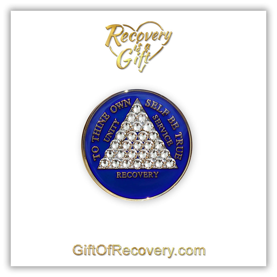 AA medallion Big Book blue with 28 genuine crystals that form the triangle entirely, this is the timeless recovery medallion, shine on with this beauty, we all have one day at a time, the AA slogan and three legacies are embossed with 14k gold-plated brass and sealed with resin for a glossy finish that will last and is scratch proof, pictured on a white 3x3 card with recovery is a gift going through an open heart at the top and giftofrecovery.com at the bottom, both in the color gold.