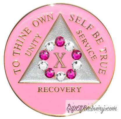 10 year princess pink AA medallion with a pearl white triangle center and pink circle, surrounding the roman numeral 10 are 10 genuine crystals, 5 dark pink and 5 clear, perfect for your favorite sober princess, to thine own self be true, unity, service, recovery, the rim of the medallion, the raised triangle outline, and the roman numeral year, are in 14k gold, sealed with resin for a glossy finish.