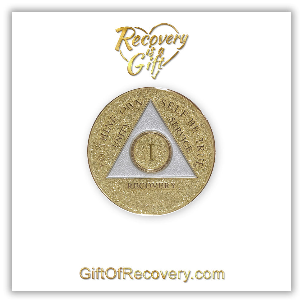 1 year AA medallion Gold glitter, with the triangle pearl white and to thine own self be true, unity, service, recovery, and the roman numeral embossed with 14k gold-plated brass, the recovery medallion is sealed with resin for a shiny finish that will last and is scratch proof, the medallion is featured on a white 3x3 card with recovery is a gift going through a heart in the center top and giftofrecovery.com at the bottom center, both are in the color gold.