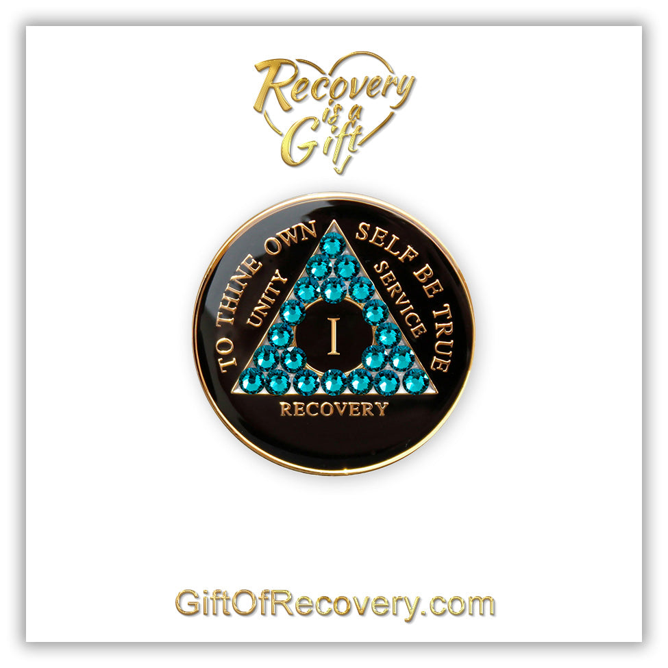 Recovery Medallion 1 Year Black Onyx with twenty-one Blue zircon crystals in the shape of the triangle, with to thine own self be true, roman numeral, and unity, service, recovery embossed with 14k Gold-plated brass, the medallion is featured on a white 3x3 card with recovery is a gift and giftofrecovery.com in the color gold. 