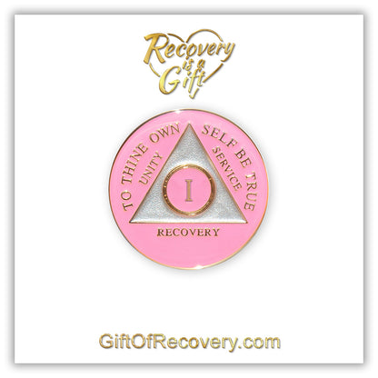 1 year AA medallion Princess pink, the ultimate girl medallion, show off your feminine side, triangle is pearl white, to thine own self be true, unity, service, recovery, and roman numeral are embossed with 14k gold-plated brass, the recovery medallion is sealed with resin for a glossy finish that will last and is scratch free, pictured on a white 3x3 card with recovery is a gift going through an open heart at the top and giftofrecovery.com on the bottom, both in the color gold.