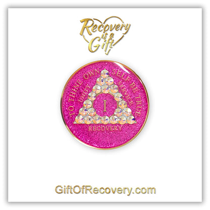 1 year AA medallion pink glitter princess adorned with 21 Aurora Borealis genuine crystals to bring out the sober princess in you the crystals are in the shape of the triangle, to thine own self be true and AA moto embossed with 14k gold-plated brass, recovery medallion is sealed with resin for a glossy finish that will last and is scratch proof, featured on a white 3x3 card with recovery is a gift and giftofrecovery.com in the color gold. 