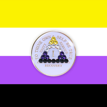 1 year AA medallion pearl white with 21 genuine crystals that form the triangle and are in the color of the Nonbinary flag, to represent pride and sobriety, the AA slogan and three legacies are embossed with 14k gold-plated brass and sealed with resin for a glossy finish that will last and is scratch proof, pictured on an image of the Nonbinary flag colors. 