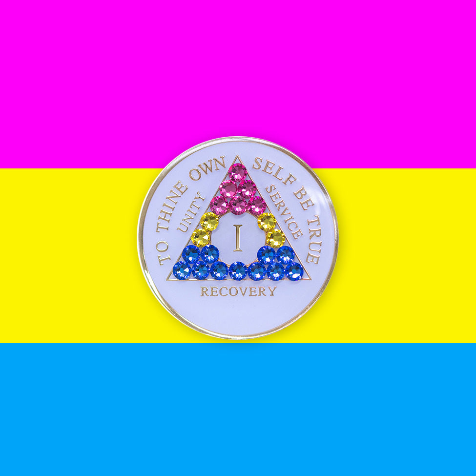 1 year AA medallion pearl white with 21 genuine crystals that form the triangle and are in the color of the Pansexual flag, to represent pride and sobriety, the AA slogan and three legacies are embossed with 14k gold-plated brass and sealed with resin for a glossy finish that will last and is scratch proof, pictured on an image of the Pansexual flag colors. 