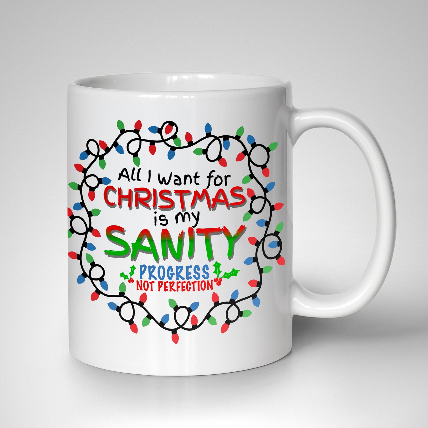 Festive lettering reading "All I Want for Christmas Is My Sanity - Progress Not Perfection," surrounded by a tangled circle of red, green, and blue Christmas lights on a 15oz white ceramic mug.