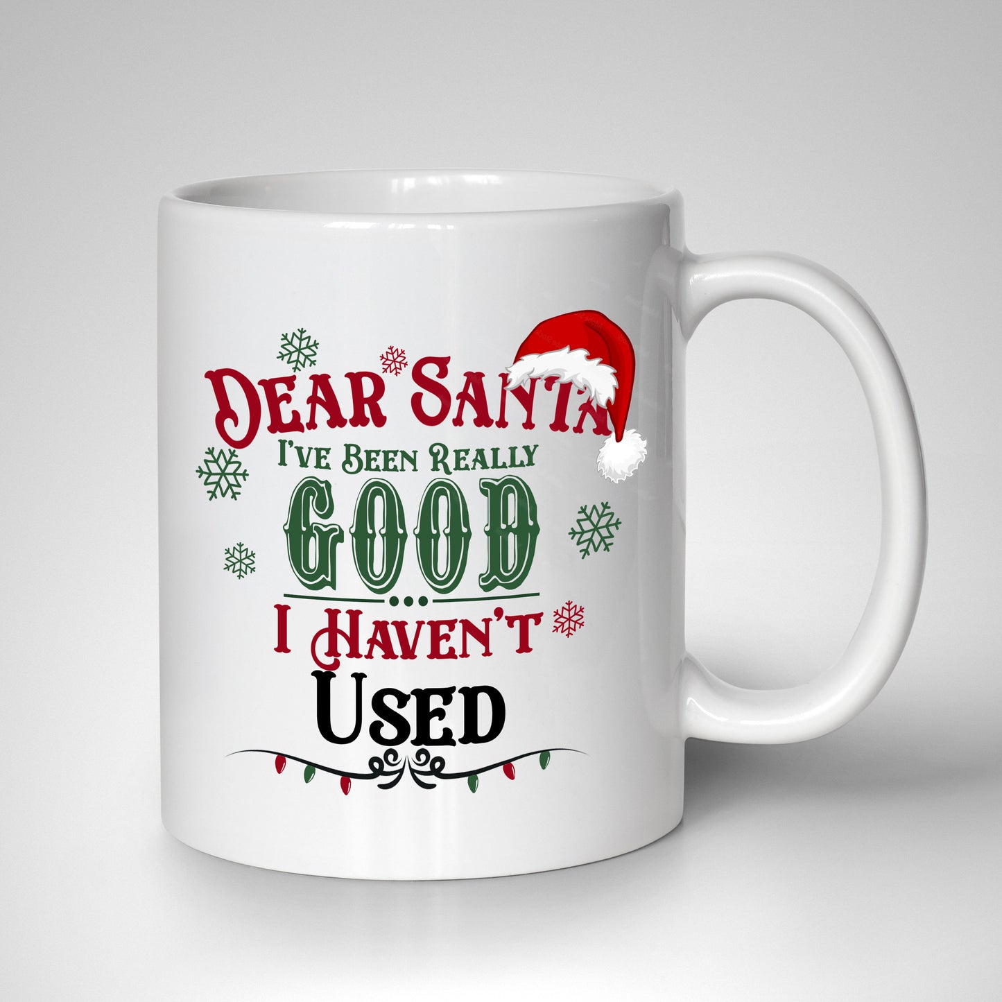 Festive lettering reading "Dear Santa, I Have Been Very Good, I Haven't Used," with a Santa hat, snowflakes, and red and green Christmas lights on a white 15oz mug.