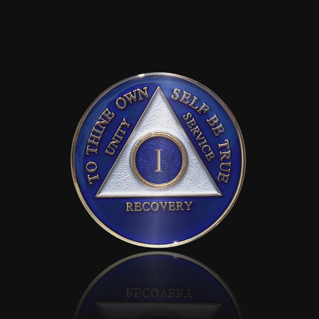 1 year AA medallion Big Book Blue, triangle is pearl white, to thine own self be true, unity, service, recovery, and roman numeral are embossed with 14k gold-plated brass, the recovery medallion is sealed with resin for a glossy finish that will last and is scratch free, featured in a 15 second video with a black background.