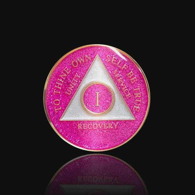 1 year AA medallion Princess pink glitter, the ultimate girl medallion, show off your feminine side, triangle is pearl white, to thine own self be true, unity, service, recovery, and roman numeral are embossed with 14k gold-plated brass, the recovery medallion is sealed with resin for a glossy finish that will last and is scratch free, featured in a 15 second video with a black background.