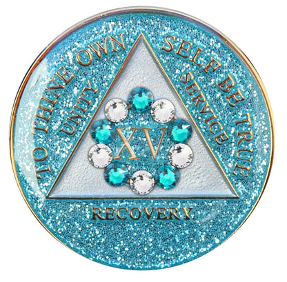 15 Year Deep-sea Aqua glitter 10th step AA medallion with 5 blue genuine crystals and 5 clear genuine crystal, formed in a circle around the year, to thine own self be true, triangle in the center and unity, service, recovery, along with rim of medallion are slightly raised in 14k gold, the center of the triangle is a soft silver tone with the circle being aqua glitter, all emphasizing action and reflection.