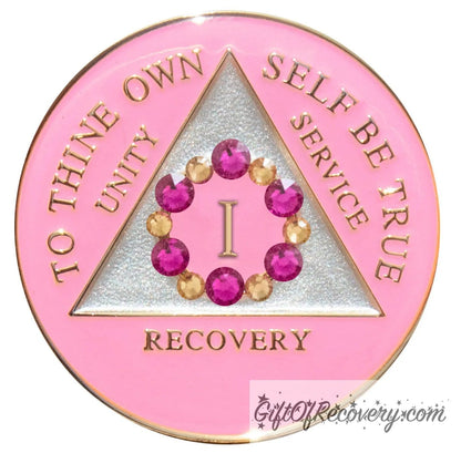 1 year AA medallion princess pink with 6 fuchsia pink genuine crystals and 6 gold to form a circle around the roman numeral to represent bloom, we grow and blossom when we work the program, triangle is pearl white with the AA slogan and three legacies embossed in 14k gold-plated brass, sealed with resin for a glossy finish.