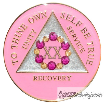 20 year AA medallion princess pink with 6 fuchsia pink genuine crystals and 6 gold to form a circle around the roman numeral to represent bloom, we grow and blossom when we work the program, triangle is pearl white with the AA slogan and three legacies embossed in 14k gold-plated brass, sealed with resin for a glossy finish.