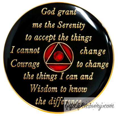 Back of AA Ruby red recovery medallion is black and has the serenity prayer, outer rim, and the circle triangle in the center embossed with 14k gold-plated brass, the circle is red and the triangle is black with one single red genuine crystal in the center of the triangle, the recovery medallion is sealed with resin for a shiny finish. 