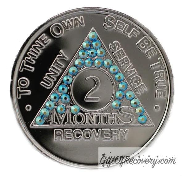 2 month aluminum AA recovery medallion with 29 light blue genuine crystals for the triangle along with the AA slogan and three legacies.