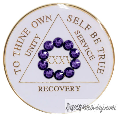 35 year AA medallion in pearl white with ten genuine purple velvet crystal in a circle representing our common welfare and personal recovery, to thine own self be true and other AA moto embossed with 14k gold-plated brass, the recovery medallion is sealed with resin for a scratch free shiny finish.